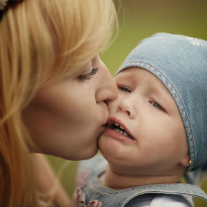 Мама целует плачущую дочь