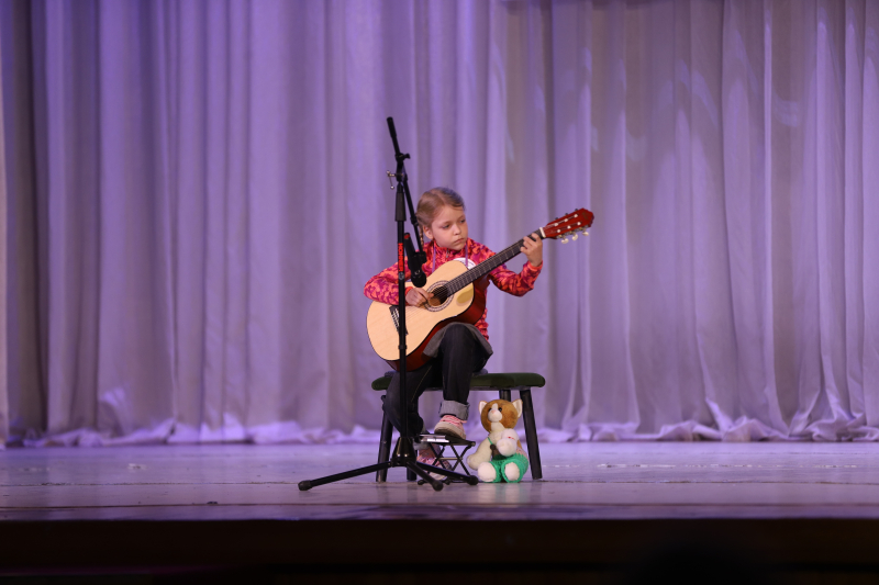 Девочка на сцене играет на гитаре
