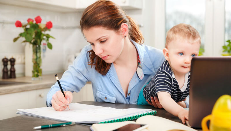 Мама пишет конспект с ребенком на руках
